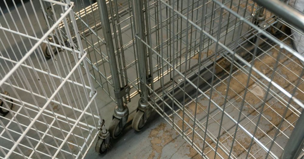 Storage Carts - High-angle view of industrial metal laundry carts in a laundry facility with textured flooring.