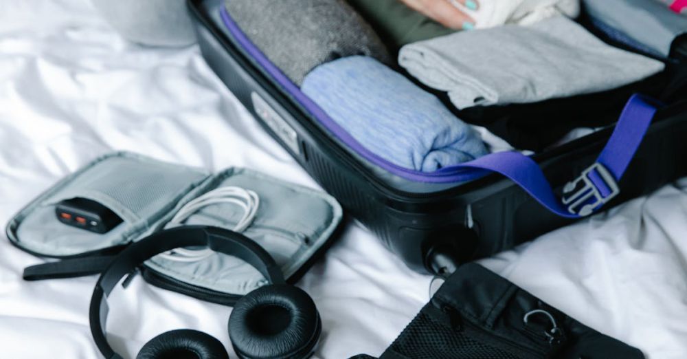 Packing Cubes - Person organizing suitcase with clothes and toiletries on bed, preparing for travel.