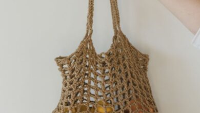 Holders - A hand holding a crocheted bag filled with yellow fruits against a plain background.