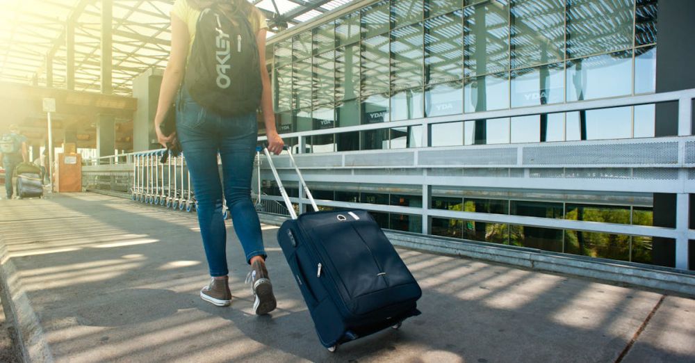 Suitcases - A woman walks with a suitcase outside an airport terminal, ready for travel.