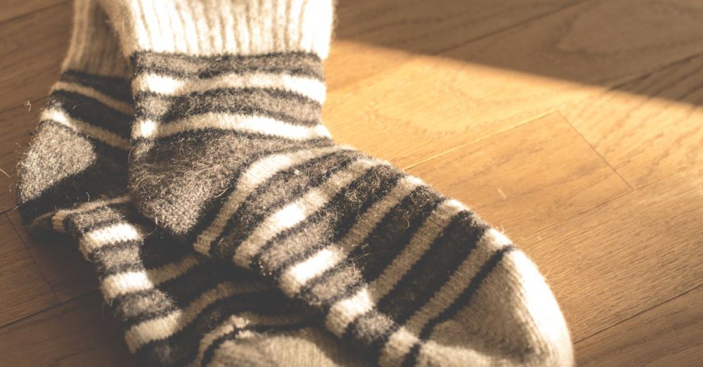 Socks - Warm knitted striped socks on a sunlit wooden floor, offering a cozy and stylish winter vibe.