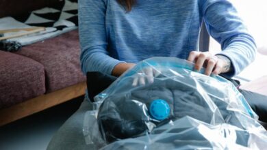 Compression Bags - Young woman using vacuum seal bags to pack clothes indoors.