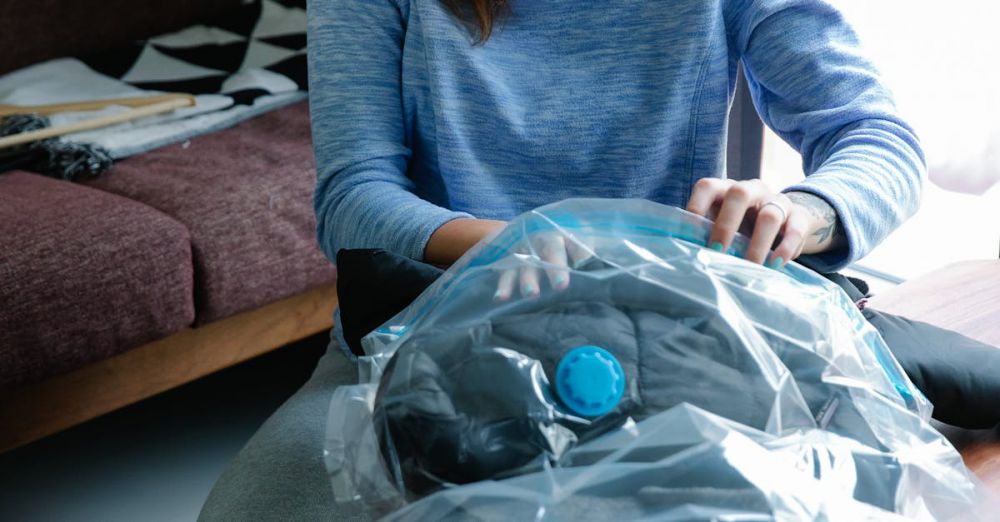 Compression Bags - Young woman using vacuum seal bags to pack clothes indoors.