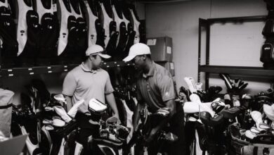 Garment Bags - Two men sorting and organizing golf bags and clubs in a storage room.