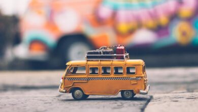 Luggage Scales - Close-up of a toy Volkswagen van with luggage, set against a colorful street backdrop, evoking summer travel vibes.