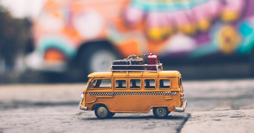 Luggage Scales - Close-up of a toy Volkswagen van with luggage, set against a colorful street backdrop, evoking summer travel vibes.