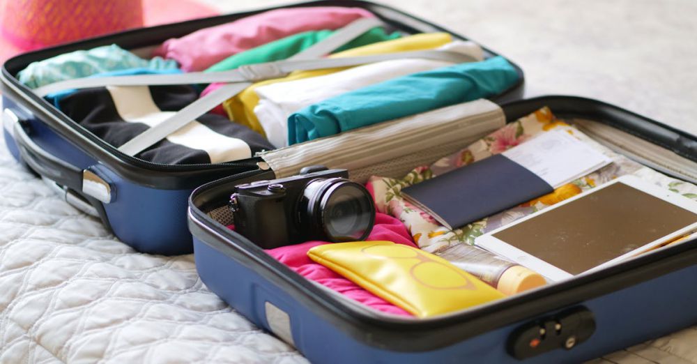 Packing Lists - Open suitcase with camera, clothes, and passport, ready for a summer vacation.