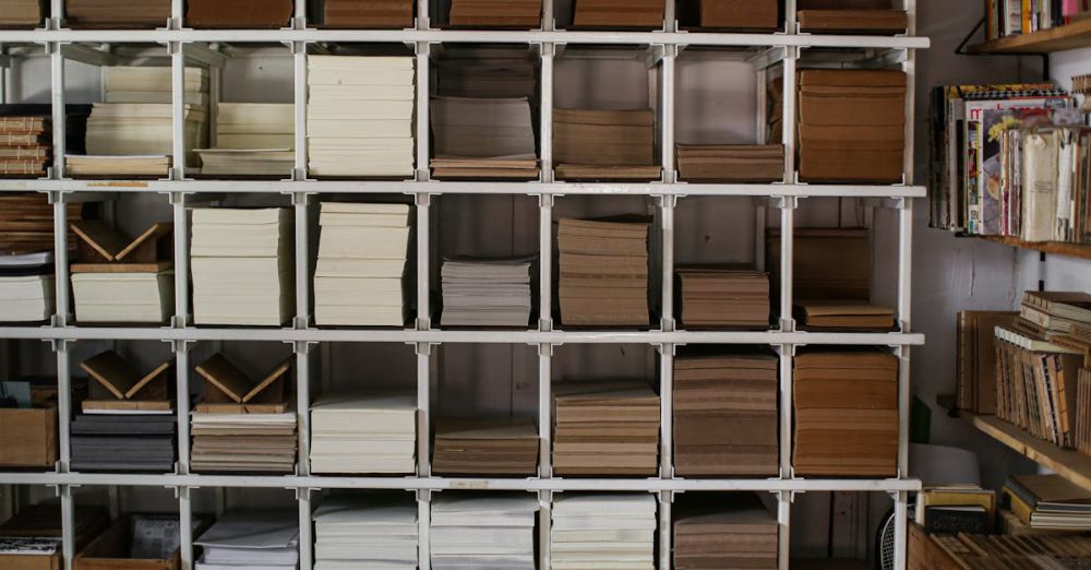 Reading Products - Neat stacks of various books and papers arranged on white shelving units.