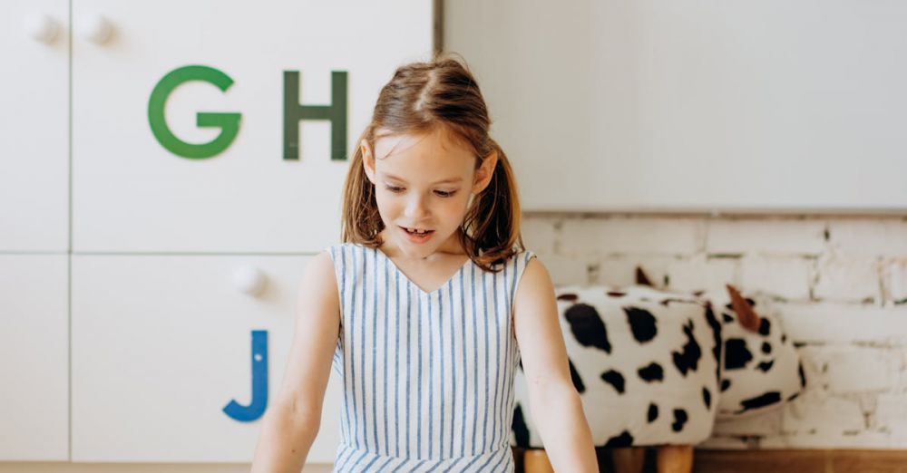 Educational Games - Young girl reading a book surrounded by educational decor indoors.