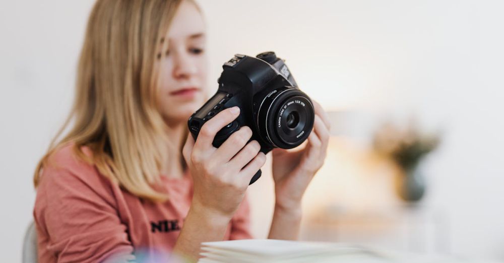 Beginner Books - Young woman examining a DSLR camera indoors with a blurred background.