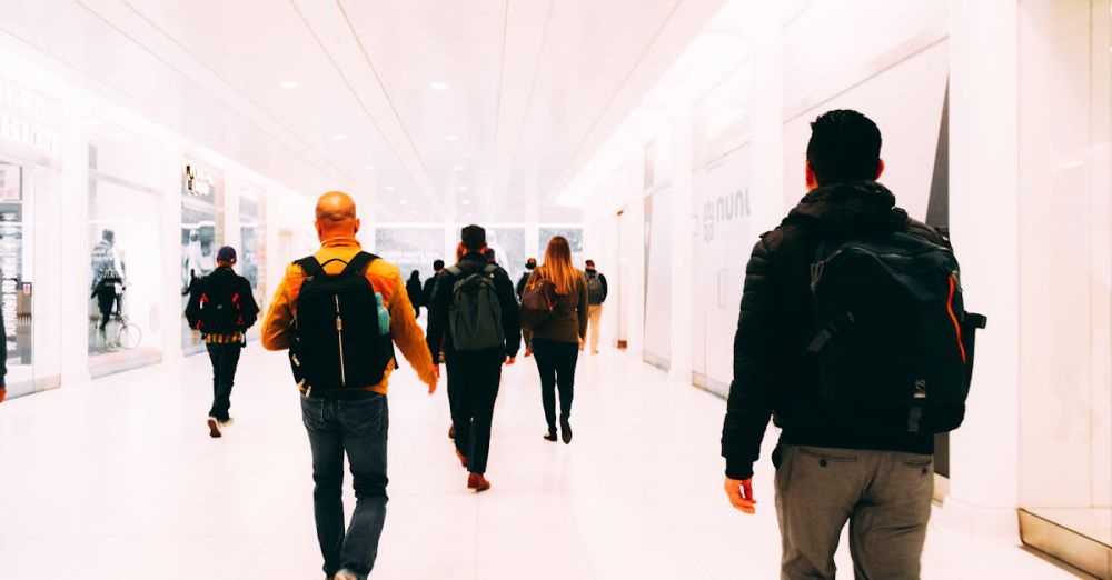 Backpacks - Group of travelers walking through a bright, modern airport terminal carrying backpacks.