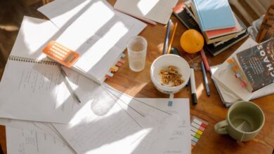 Math Workbooks - A cluttered study table with books, notes, and study materials in natural light for focused exam preparation.