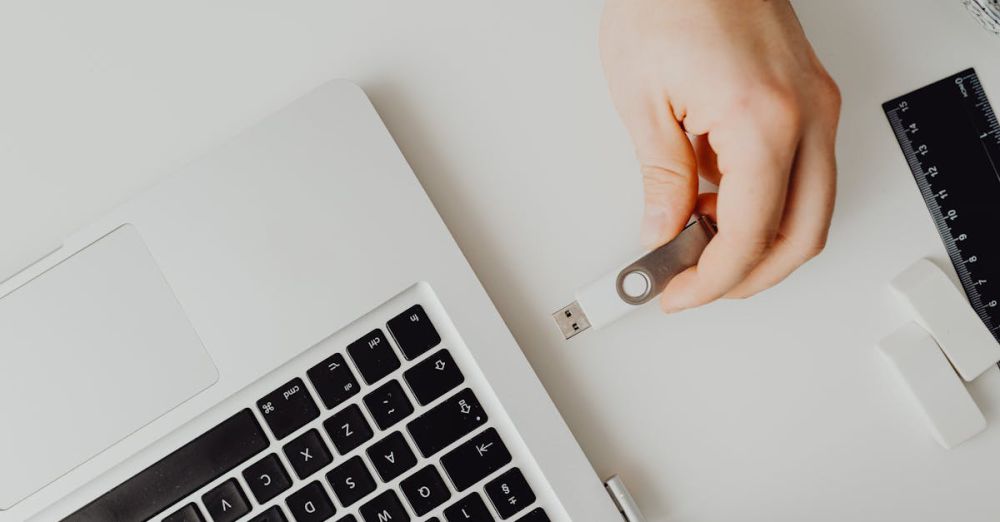 Flash Drives - Hand inserting USB drive into laptop. Modern tech connection concept.