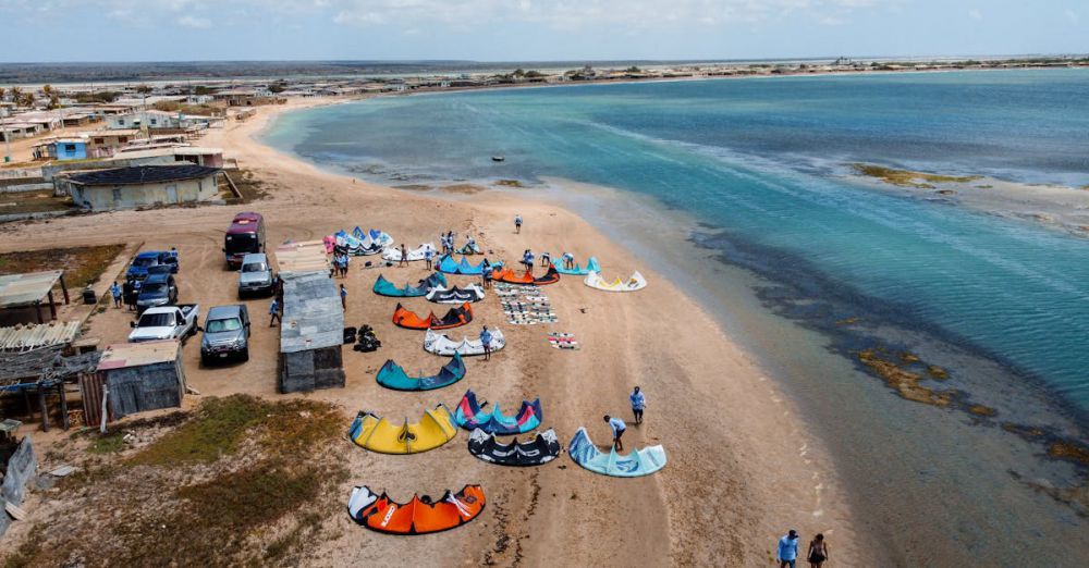 Activity Kits - A vibrant aerial view of kitesurfers setting up on Santa Rita Beach, Venezuela.