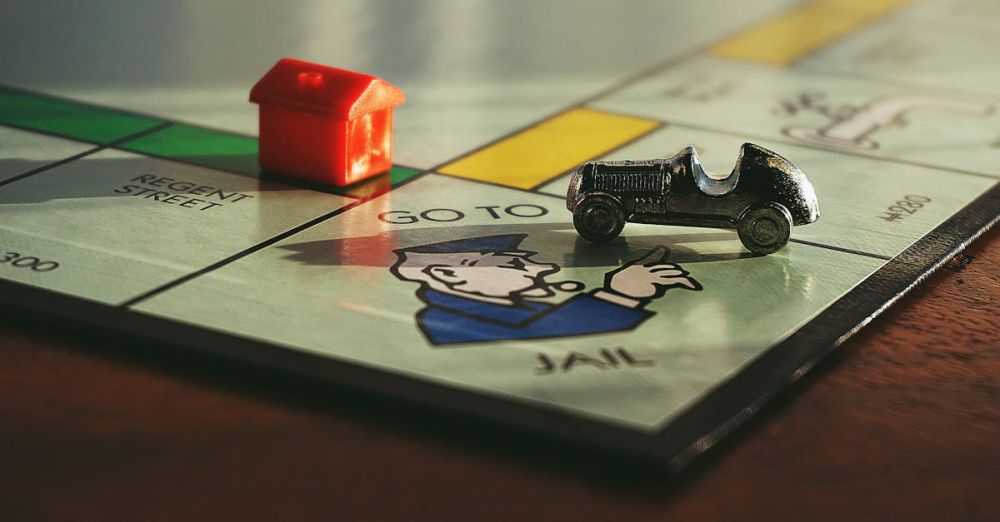 Board Games - Close-up shot of a Monopoly board game featuring a toy car and a red house on 'Go to Jail'.