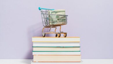 Social Books - A small shopping cart with dollar bills placed on a stack of books, symbolizing financial literacy.