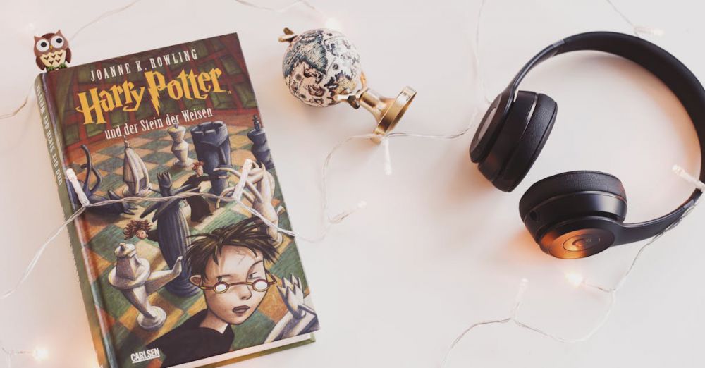 Audiobook Subscriptions - Minimalist setup with Harry Potter book, headphones, and string lights for a cozy reading experience.