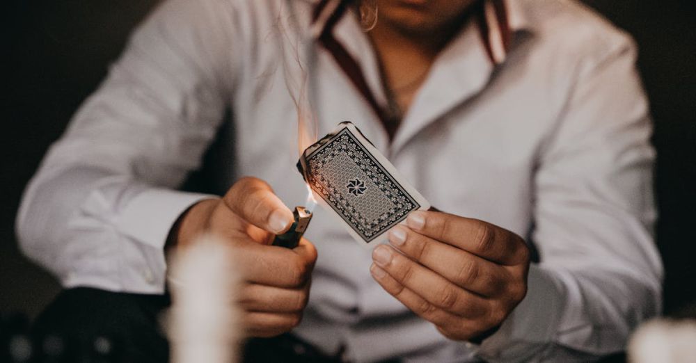 Flash Card Sets - Close-up of a man setting a playing card on fire with a lighter indoors.