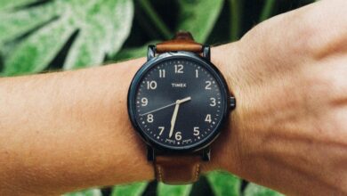 Outdoor Watches - Man's wrist wearing a stylish watch in front of lush green foliage showcasing nature.