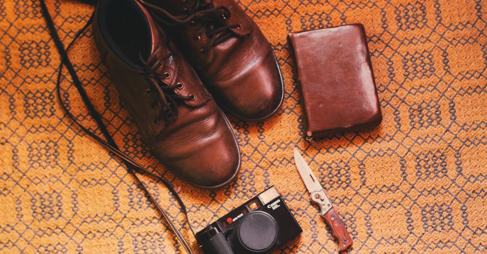 Shoes - Brown leather shoes, a vintage camera, knife and wallet on a patterned background.