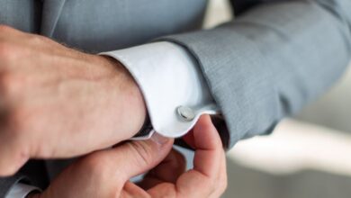 Cufflinks - Close-up of a man's hands adjusting his cufflinks on a gray suit sleeve, showcasing elegance.