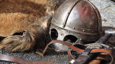 Leather Straps - Close-up of medieval armor, helmet, and sword in a classic setting.